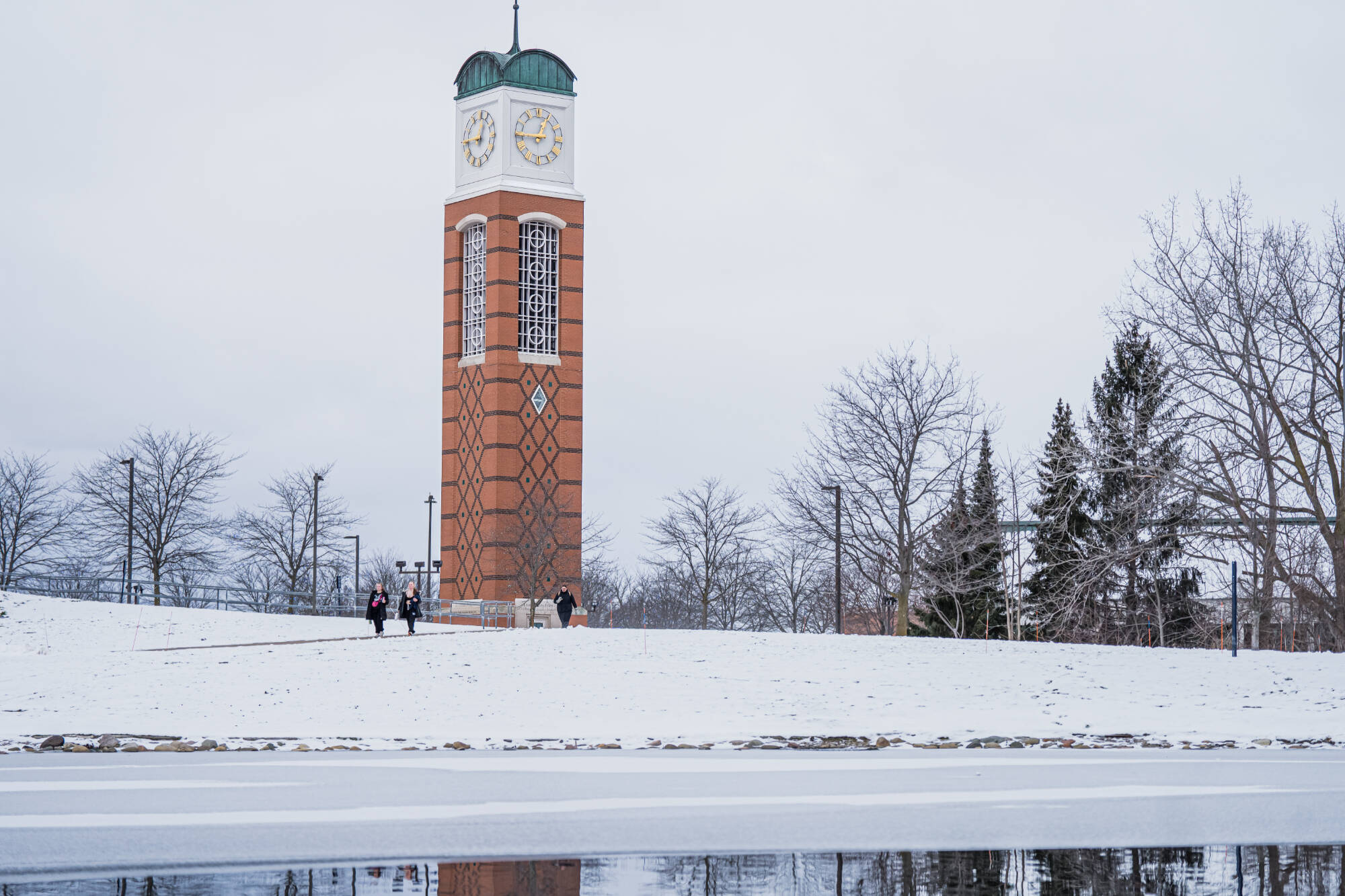 Students walking in front of the clock tower and Zumberge pond on December 8th.